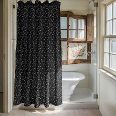 a bathroom with a black shower curtain next to a bath tub