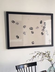 a vase with flowers sitting on top of a wooden table next to a framed photo