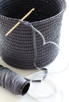 a basket with yarn and knitting needles next to it on a white surface, ready to be sewn