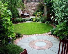 a small garden with green grass and plants around the area, surrounded by greenery