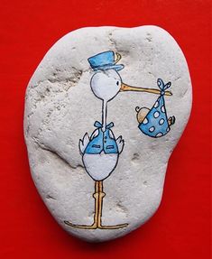 a painted rock with a stork carrying a baby on it's back