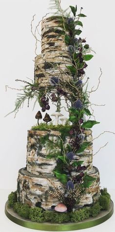 a three tiered cake with moss and flowers on it