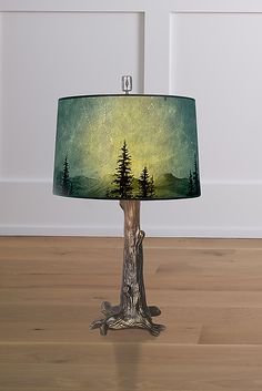 a lamp that is on top of a wooden floor in front of a white wall