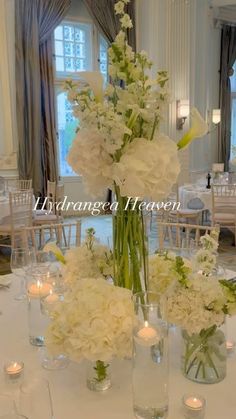 white flowers and candles are arranged in glass vases on a table at a wedding reception