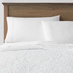 a bed with white sheets and pillows on it