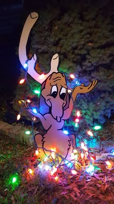 a light - up moose is sitting in the grass with its lights on it's back legs