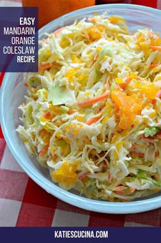 coleslaw salad with oranges and carrots in a blue bowl on a checkered tablecloth