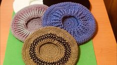 four crocheted rugs sitting on top of a wooden table