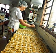 a person in a kitchen preparing food on top of a long table with lots of pans