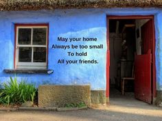 a blue house with a poem written on the front door and window above it that says, may your home always be too small to hold all your friends