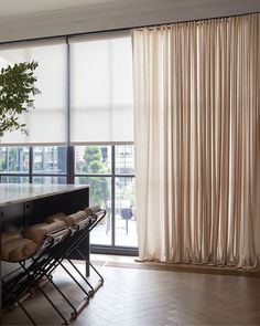 a living room filled with furniture and a large window covered in white drapes next to a plant