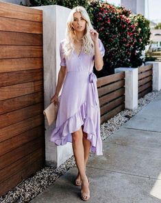 a woman in a purple dress leaning against a wall