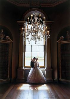 a bride and groom standing in front of a chandelier