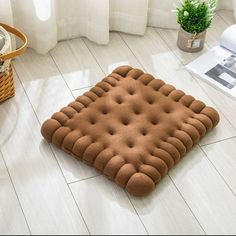 a brown dog bed sitting on top of a white floor next to a basket and potted plant