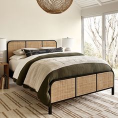 a bedroom with a bed, nightstand and large window overlooking the trees in the background