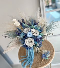 a hat with flowers and feathers on top of a wooden table next to a window