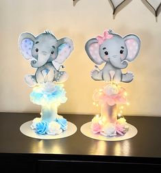 two small elephant figurines sitting on top of a table next to each other