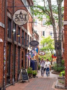 two people walking down the street in front of some shops