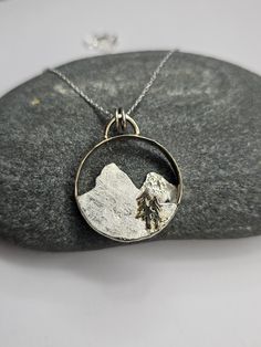 This mountain pendant is handmade from upcycled Yellow Gold and Sterling Silver. The base ring is 14k yellow gold the mountains are Sterling Silver with 18k Yellow Gold and there are 14k yellow Gold trees. I'm an avid hiker and nature inspires me to create jewelry. I'll include a Sterling silver 18 inch necklace. Hammered Yellow Gold Nature-inspired Jewelry, Nature-inspired Hammered Jewelry For Anniversary, Nature-inspired Jewelry With Large Round Pendant, Nature-inspired Yellow Gold Round Pendant Jewelry, Nature-inspired Round Pendant Jewelry For Anniversary, Nature-inspired Jewelry With Natural Inclusions In Round Pendant, Mountain Pendant, Mountain Tree, Organic Textures