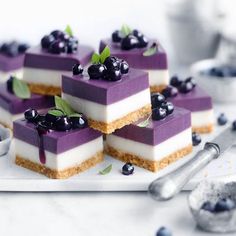 small desserts with blueberries and cream on a white plate next to spoons