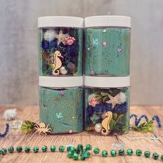 three jars with sea creatures on them sitting next to beads