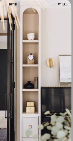 an open bookcase in the corner of a room with plants and other items on it