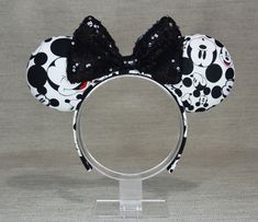 a minnie mouse ears headband with black and white polka dots on it, sitting on a clear acrylic stand