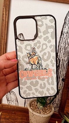 a person holding up a phone case that has a cowgirl on it and an animal print