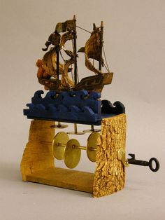 a wooden model of a pirate ship on display with an antique key chain and wind chime