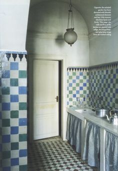 a bathroom with blue and green tiles on the walls, two sinks and a mirror