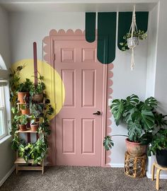 a pink door in the corner of a room with potted plants