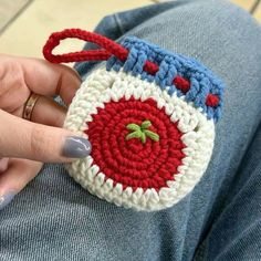 a woman's hand is holding a crocheted bag with an apple on it