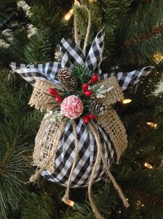 a christmas ornament hanging from a tree with pine cones and plaid ribbon on it