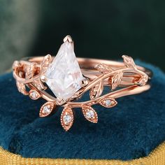 a close up of a ring on a blue velvet cushion with gold leaves and diamonds