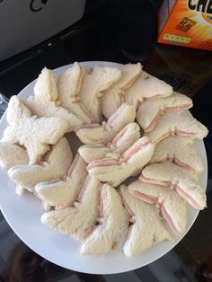 a white plate topped with cut up sandwiches on top of a counter next to a box of cheetos