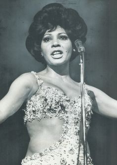 an old black and white photo of a woman singing into a microphone with her arms outstretched