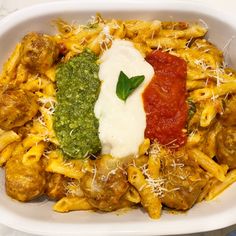 a white plate topped with pasta and meat covered in sauce, parmesan cheese and pesto