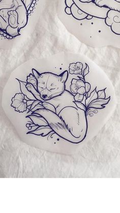 three plates with designs on them sitting on top of white paper and one has an image of a sleeping fox