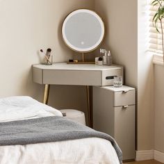 a bedroom with a bed, desk and mirror on the wall next to a potted plant