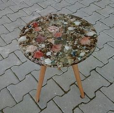 a small table with shells on it sitting on the ground next to a brick walkway