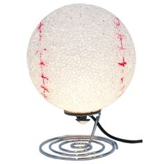 a baseball lamp on a metal base with a white ball and red stitches painted on it