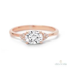 a rose gold engagement ring with two diamonds on the band and an oval center stone