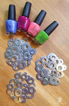 five different nail polishes are sitting on a wooden table next to some metal circles