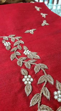 a red table cloth with silver embroidered flowers and leaves on the edge, along with pearls