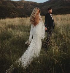 a bride and groom walking through tall grass