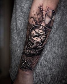 a man's arm with a compass and rope tattoo on the left side of his arm