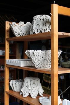 the shelves are filled with crocheted baskets and doily dishes in white lace