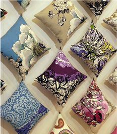 a bunch of pillows that are hanging on a wall in front of each other with different designs