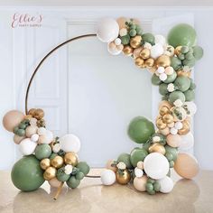 a balloon arch with gold, white and green balloons in the shape of a circle