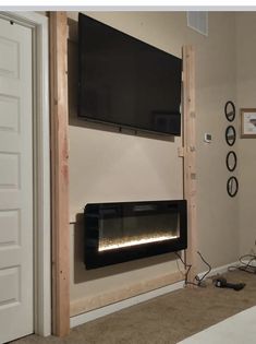 a room with a television mounted on the wall and a fire place in front of it